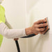 Angle view of Mini Flex Air sanding tool attached to vacuum, refinishing drywall detail