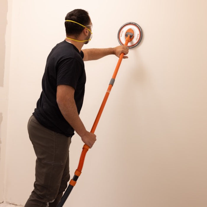 User sanding ceiling with Radius360 Dust-Free Conversion Kit attached to dust-extraction vacuum