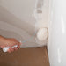 Drywall compound roller applying joint compound to inside corner taped seam
