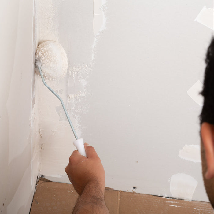 Drywall compound roller applying joint compound in an inside corner seam