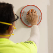 Contractor using Full Circle Radius360 drywall sanding tool in handheld configuration on wall